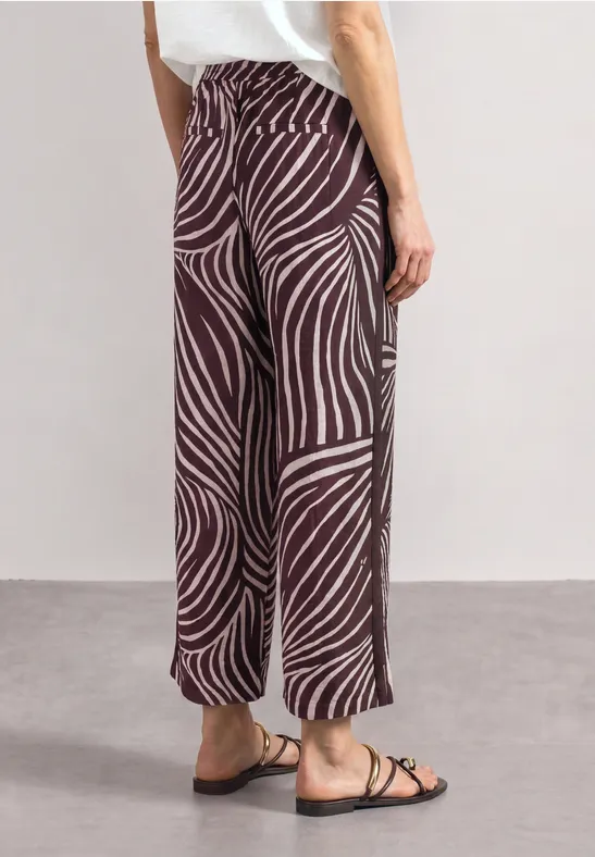 Wijde broek met bruin-beige zebraprint, rechte pasvorm, enkel-lang, gecombineerd met platte sandalen.