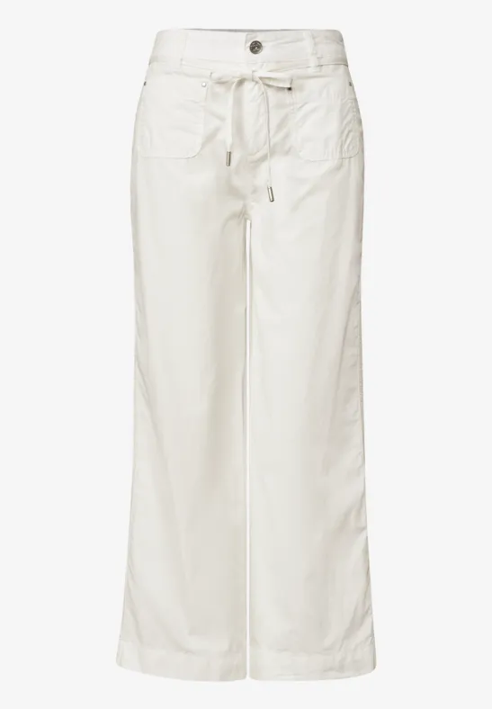 Weiße, weite Hose mit hohem Bund, aufgesetzten Taschen und Bindegürtel.