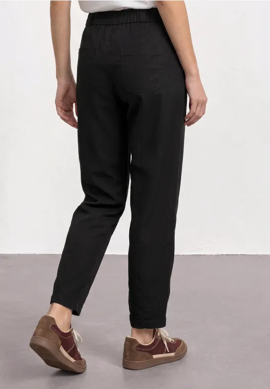 Persoon van achteren in een zwarte casual broek en bruine sneakers