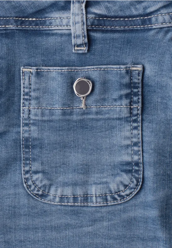 Blauer Jeansstoff mit kleiner aufgesetzter Tasche, in der ein silberner Schlüsselring steckt.