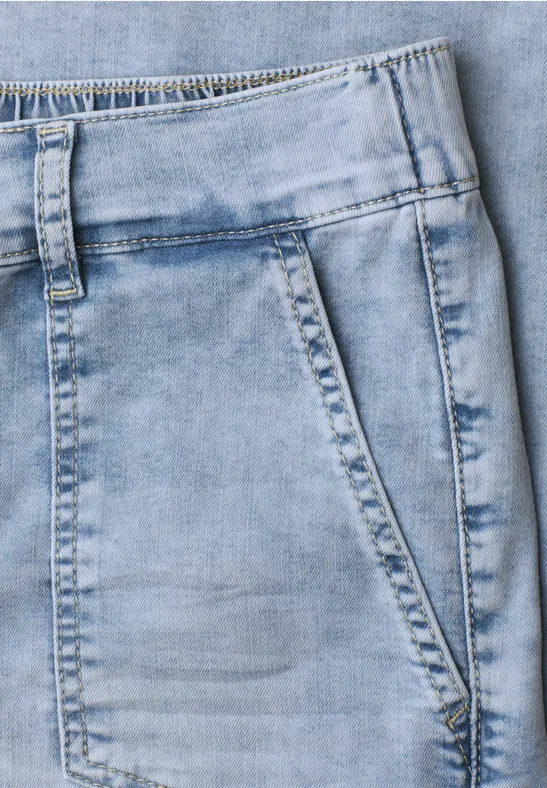 Nahaufnahme einer hellblauen Jeanshose mit sichtbarer Fronttasche und Nahtdetails.