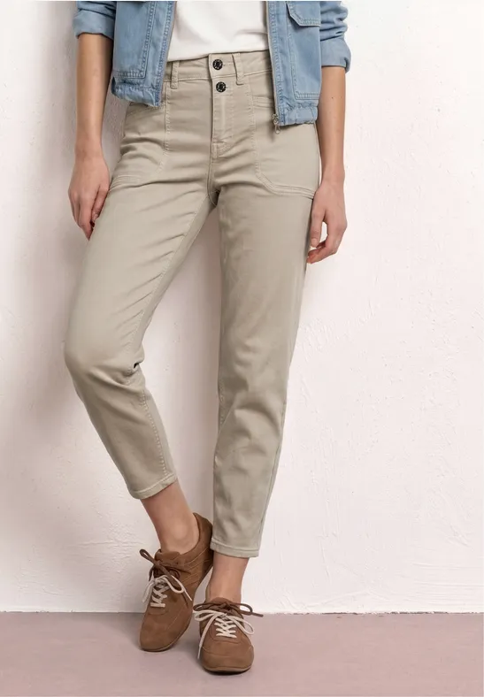 Beige, hoch taillierte Hose mit zwei Knöpfen, lässig bis zum Knöchel, dazu braune Schnürschuhe.