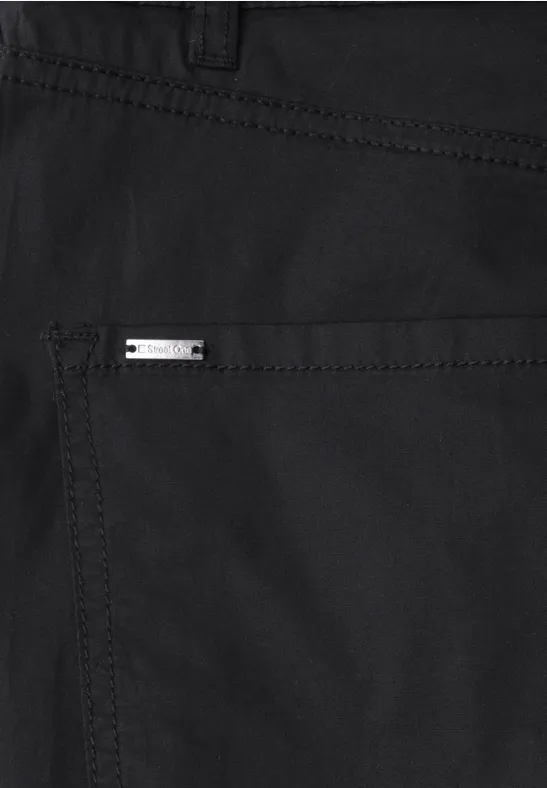 Detailaufnahme einer schwarzen Hose mit silbernem Markenlogo auf Gesäßtasche.