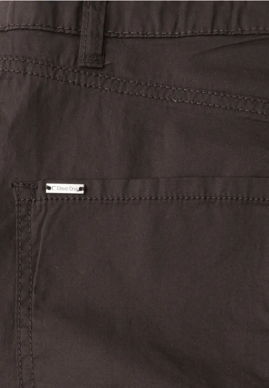 Nahaufnahme einer dunkelbraunen Stoffhose mit Tasche und kleinem Metall-Label.