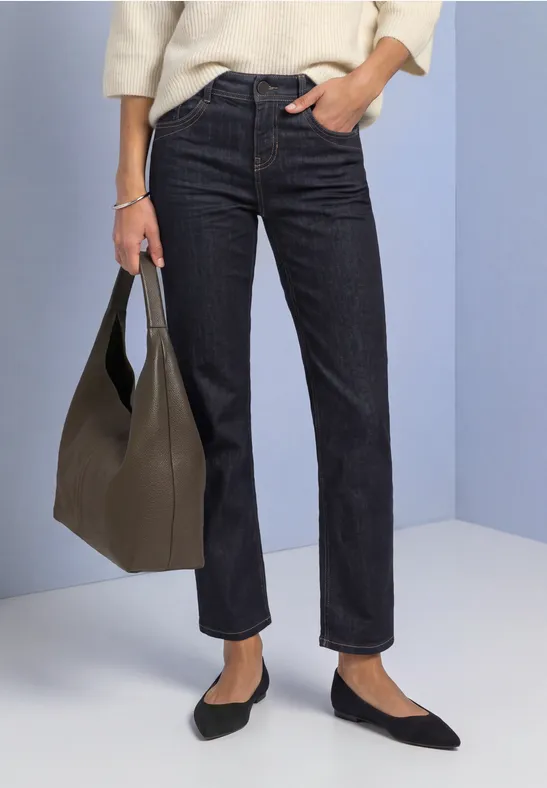 Dunkelblaue, gerade geschnittene Jeans, schwarze Ballerinas und eine olivgrüne Handtasche.