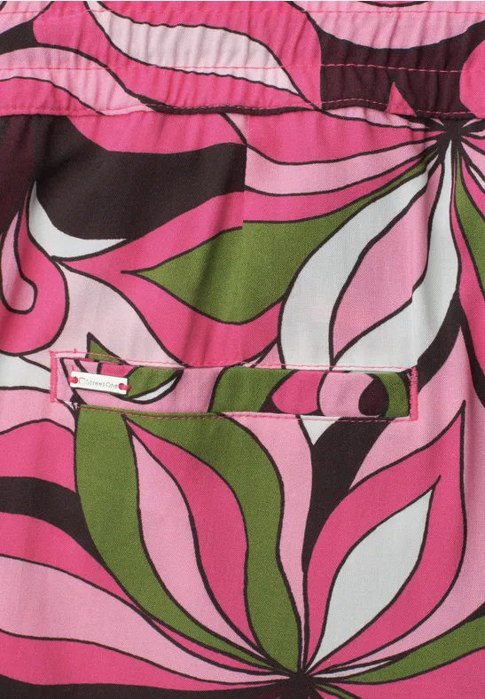 Felle psychedelische bloemenprint in roze, groen, wit en zwart op stof.