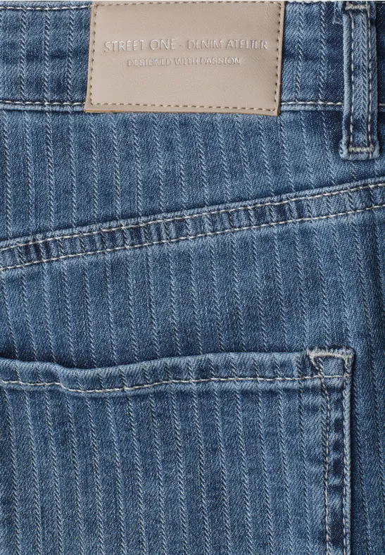 Close-up van een blauwe spijkerbroekzak met streeppatroon en een leren label.