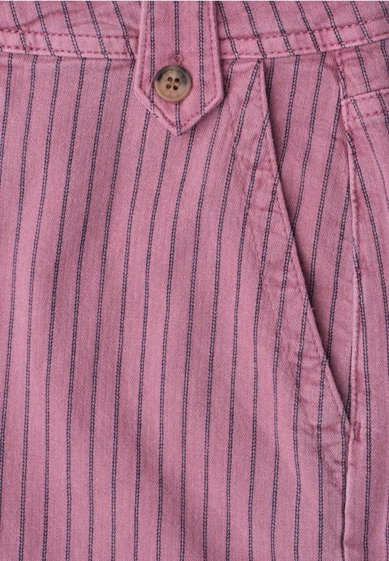 Close-up van een roze broek met zwarte strepen, knoop en zijzak.