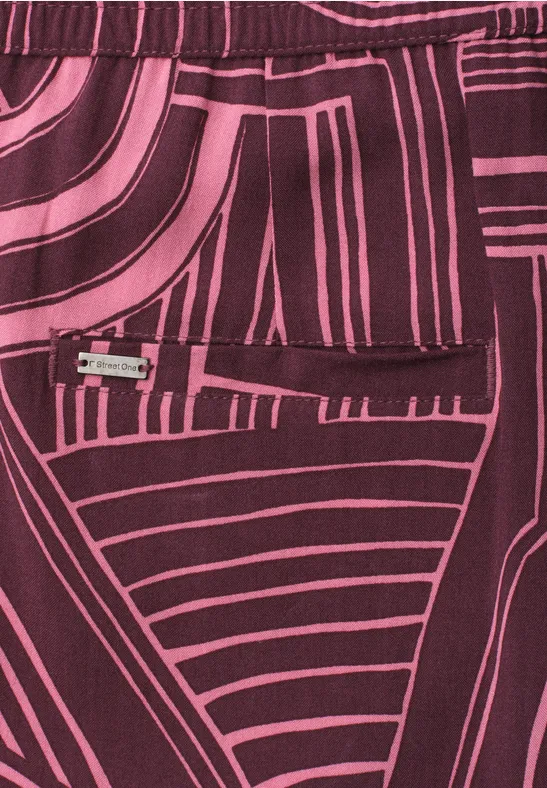 Motif abstrait sur tissu rose et bordeaux aux lignes géométriques.