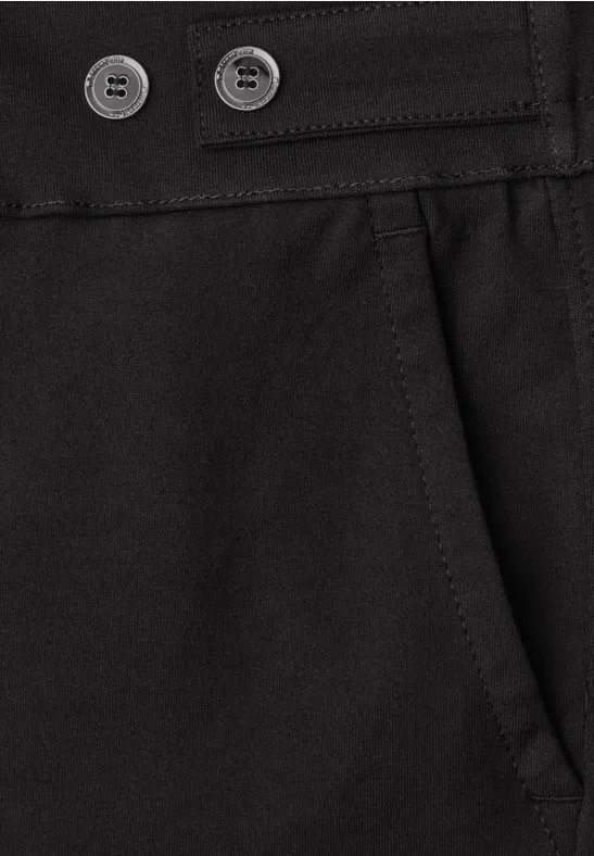 Close-up van een zwarte broek met steekzak en dubbele knoopsluiting.