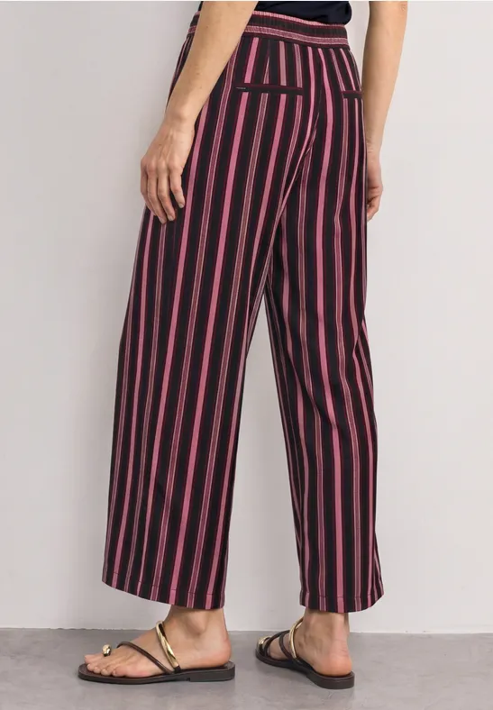 Damenhose, weite Beine, schwarz-rot gestreift, hohe Taille, knöchellang, mit Sandalen kombiniert.