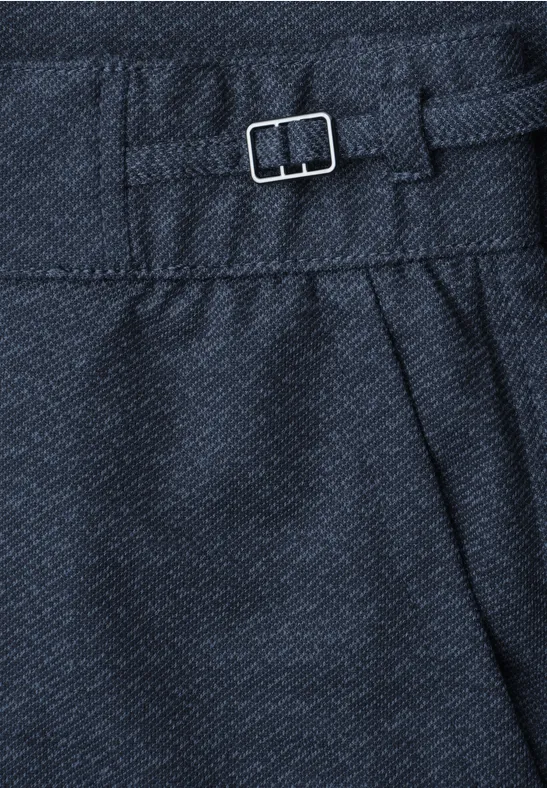Close-up van marineblauw stof met een klein metalen gespje en plooien.