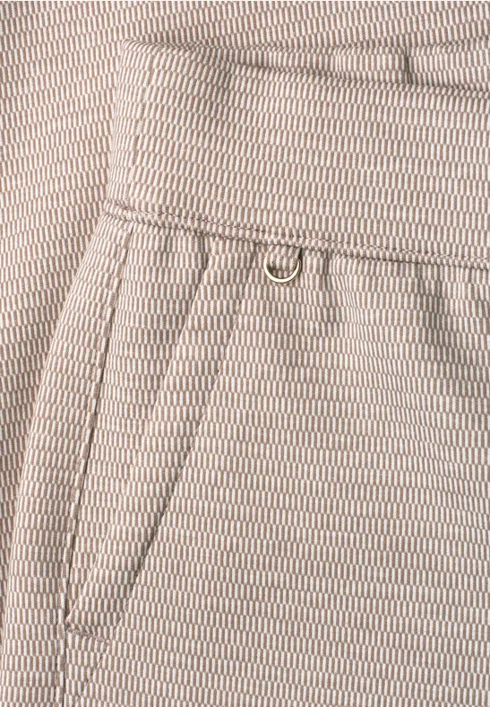 Detailaufnahme einer beigen Hose mit Tasche und Metallring.