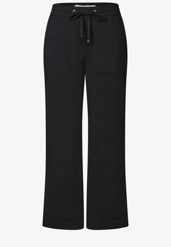 Zwarte, losvallende broek met trekkoord en wijde pijpen.