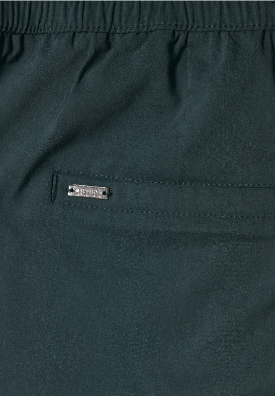 Nahaufnahme einer dunklen Hose mit Reißverschlusstasche und Metalllabel.