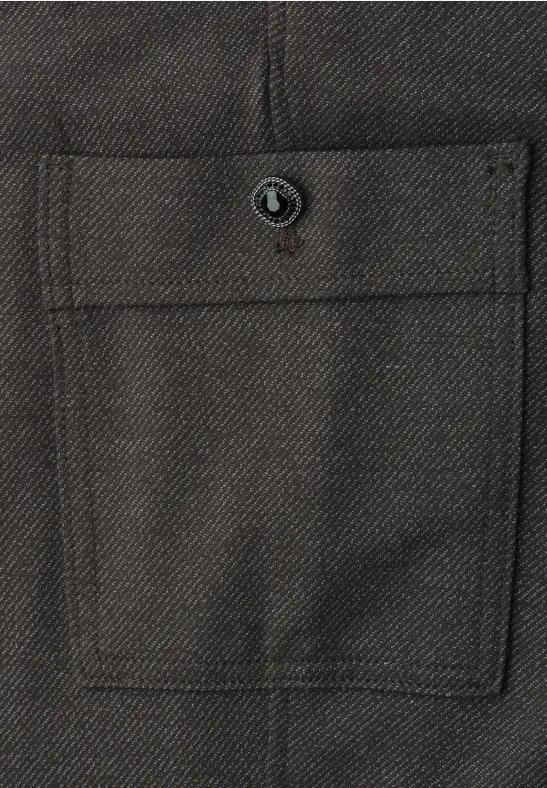 Nahaufnahme einer aufgesetzten Tasche aus dunkelgrauem Stoff mit Knopf und gerader Klappe
