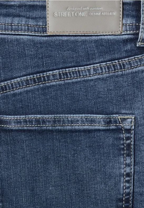 Zbliżenie na ciemnoniebieski denimat z dwoma kieszeniami i metką marki na pasie.
