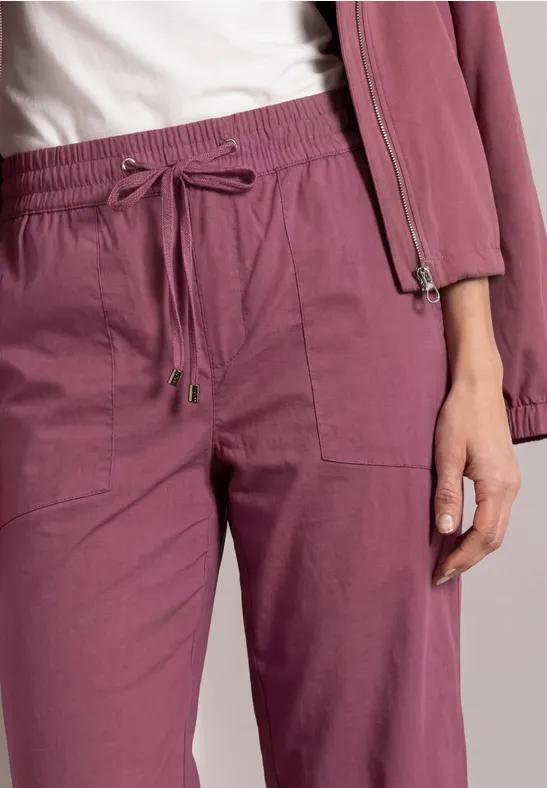 Nahaufnahme von pinken, locker sitzenden Jogginghosen mit Kordelzug und aufgesetzten Taschen.