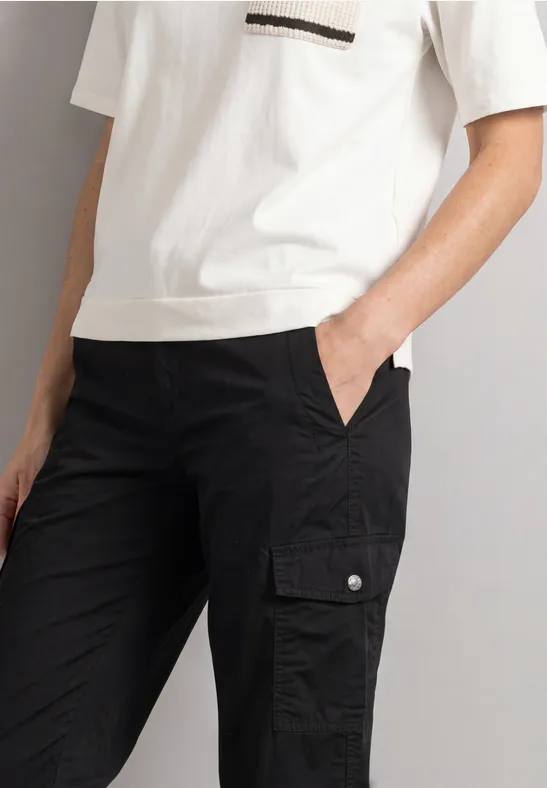Person trägt weißes T-Shirt und schwarze Cargohose mit Taschen.