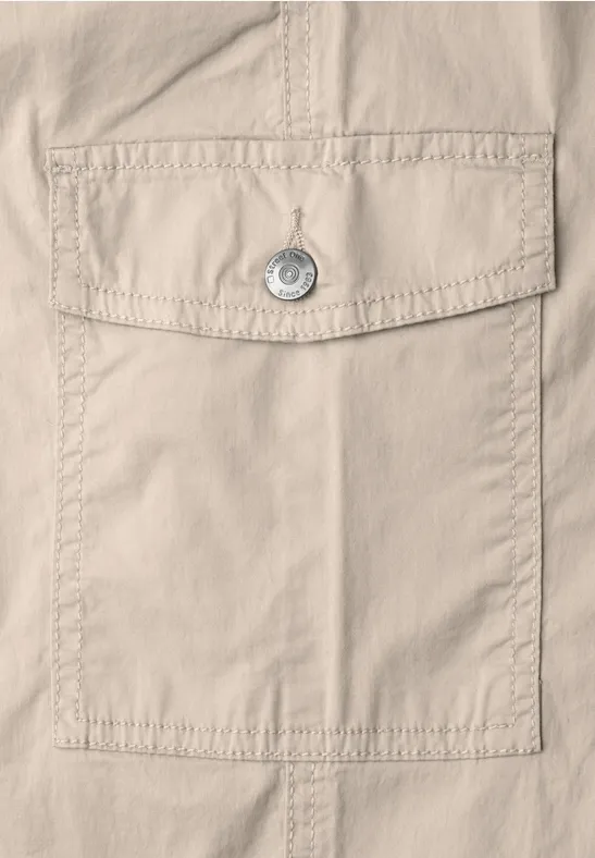 Nahaufnahme einer beigen Stofftasche mit Klappe, Knopf und sichtbaren Nähten.