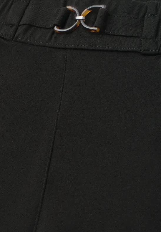 Schwarze Hose mit elastischem Bund und dekorativem Gürtel mit goldenen Ringen.