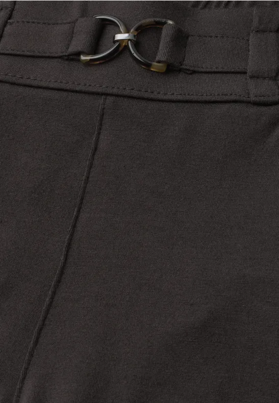 Detail eines schwarzen Hosen- oder Rockbunds mit Gürtel und goldfarbenen Metallringen.