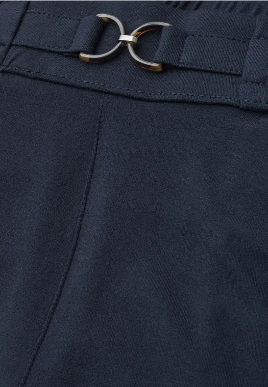 Dunkelblaue Hose aus Stoff mit hohem Bund, verziert durch einen schmalen Gürtel und goldfarbene Doppelschnalle.