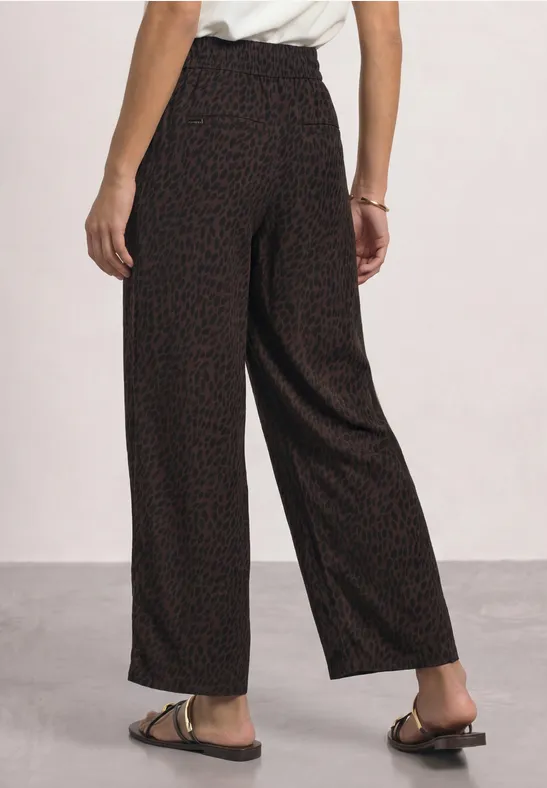 Schwarz-rote, weite Damenhose mit Feinstrukturmuster, hoher Bund, locker fallend, kombiniert mit flachen Sandalen.