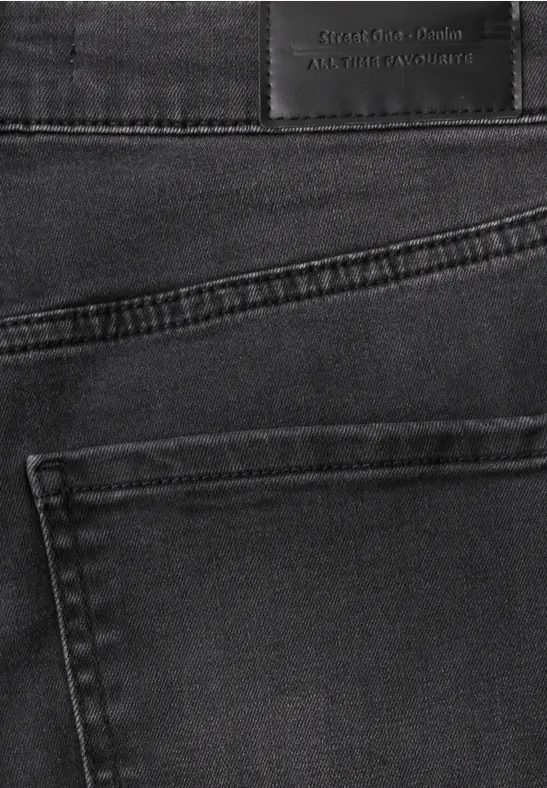 Close-up van een zwarte spijkerbroek met achterzak en zichtbaar label in de taille