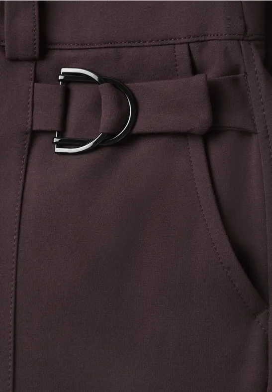 Nahaufnahme eines dunkelbraunen Hosenbunds mit seitlicher Tasche und D-Ring-Gürtel.
