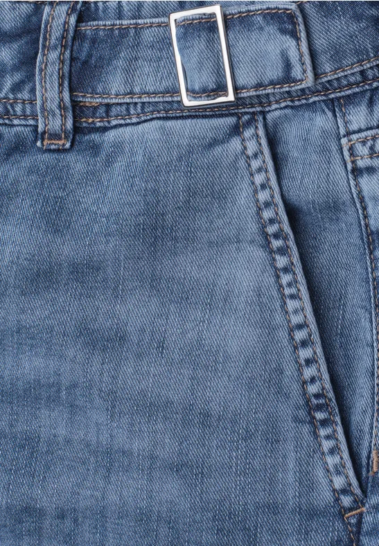 Close-up van een blauwe spijkerbroek met zak, tailleband en zilverkleurige gesp.