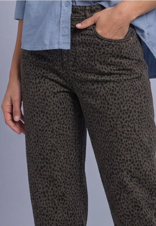 Person trägt olivgrüne Hose mit schwarzem Leopardenmuster, Hand in Tasche, hellblaues Hemd sichtbar.