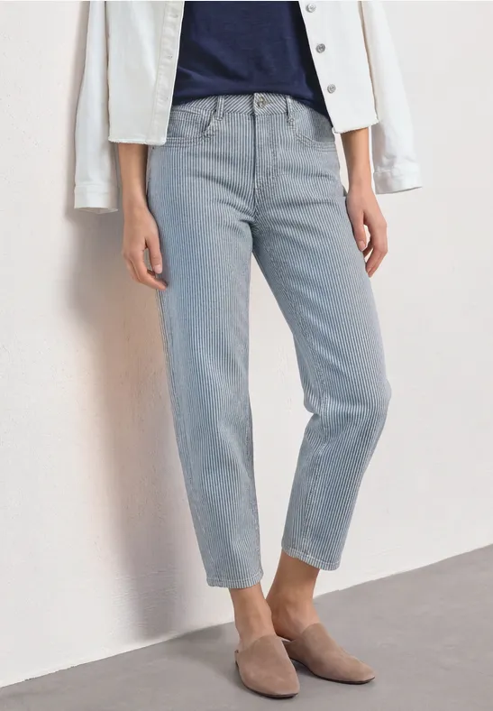 Jeans clairs droits, t-shirt bleu marine, veste blanche et chaussures beiges à bouts pointus.