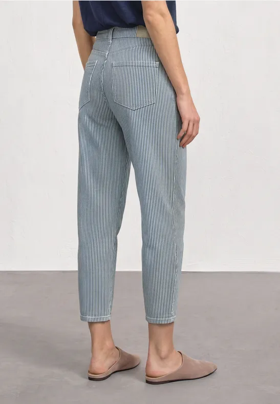 Vue arrière d'une personne en jean bleu clair taille haute et mocassins beiges.