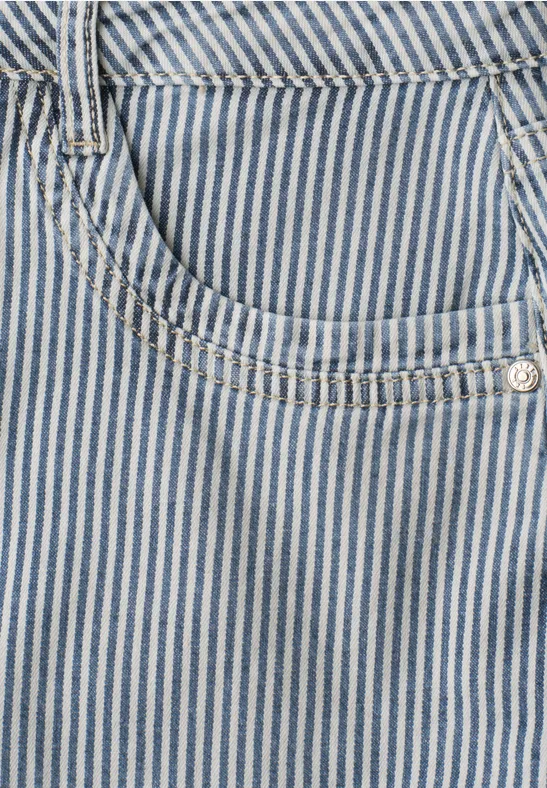 Gros plan d'une poche en denim bleu à fines rayures blanches, avec rivet argenté et coutures décoratives.