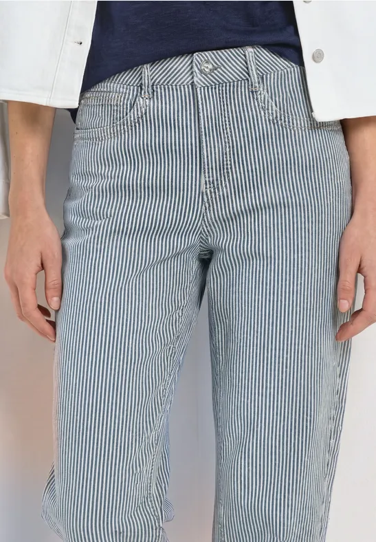 Personne porte un jean à rayures bleu et blanc taille haute, associé à un top bleu marine et une veste blanche.