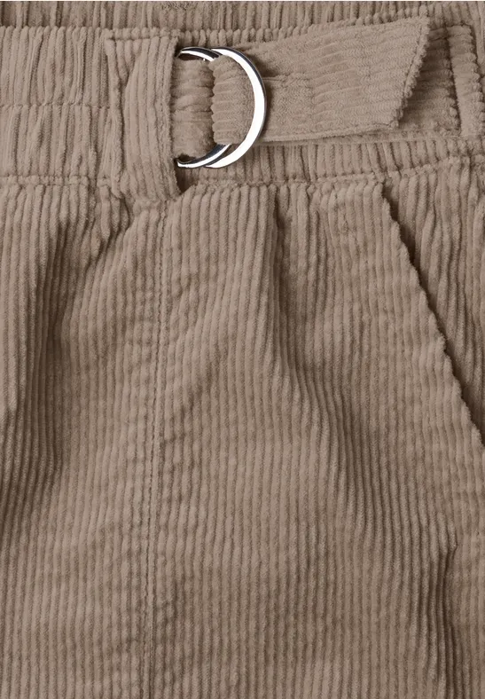 Gros plan d’un pantalon en velours côtelé beige, taille élastique avec poche et boucle en D.