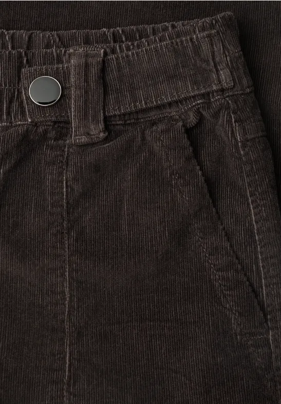 Close-up van een bruine ribfluweelbroek met elastische taille, riemlussen en zijzak.