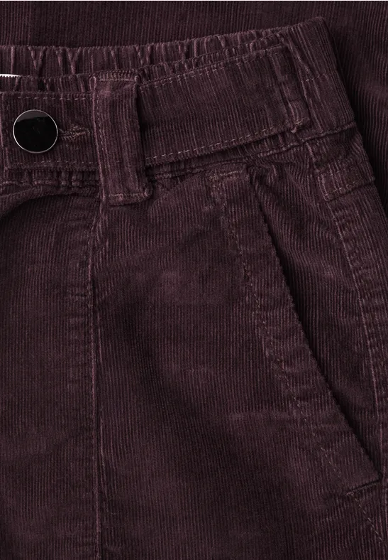 Nahaufnahme einer dunkelroten Cordhose mit Bund, Gürtelschlaufen und Seitentasche.
