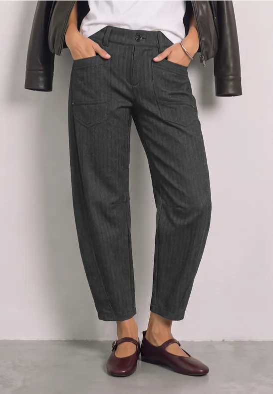 Damen in grauen Nadelstreifen-Hosen, weißem Shirt und dunkelroten Mary-Jane-Schuhen.