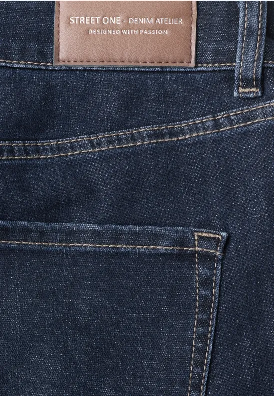 Gros plan sur la poche arrière d'un jean foncé avec un patch en cuir 'STREET ONE Denim Artwork'.