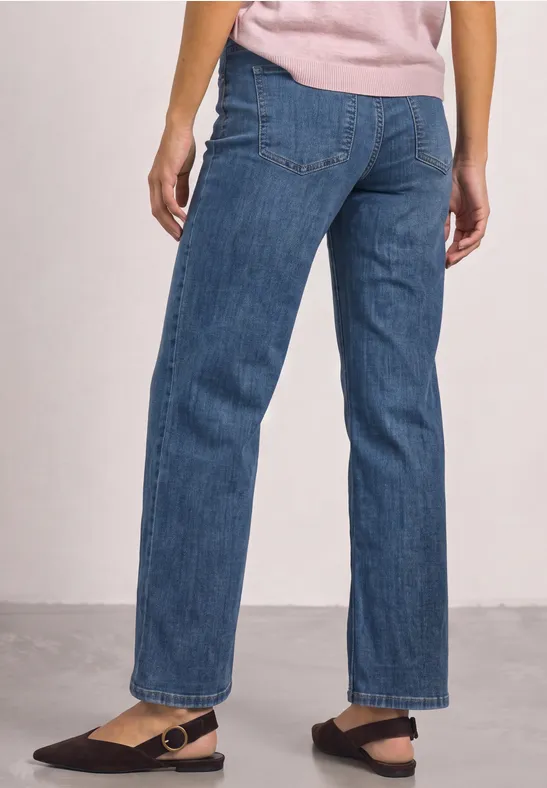 Frau trägt gerade geschnittene blaue Jeans und schwarze Riemchensandalen.