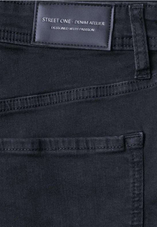 Gros plan d’un jean noir avec étiquette visible et coutures de poche.