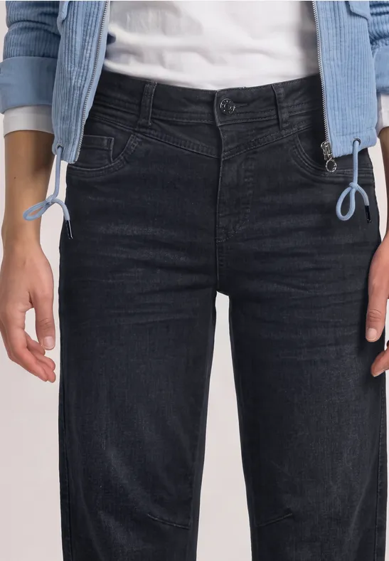 Une personne porte une veste en jean bleu clair, un t-shirt blanc et un jean noir.