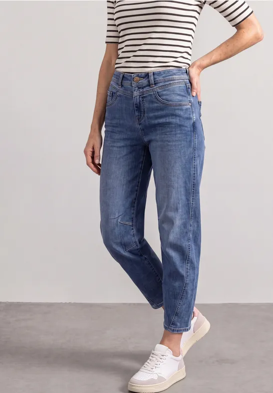 Frau in blauen Jeans, gestreiftem Shirt und weißen Sneakern.