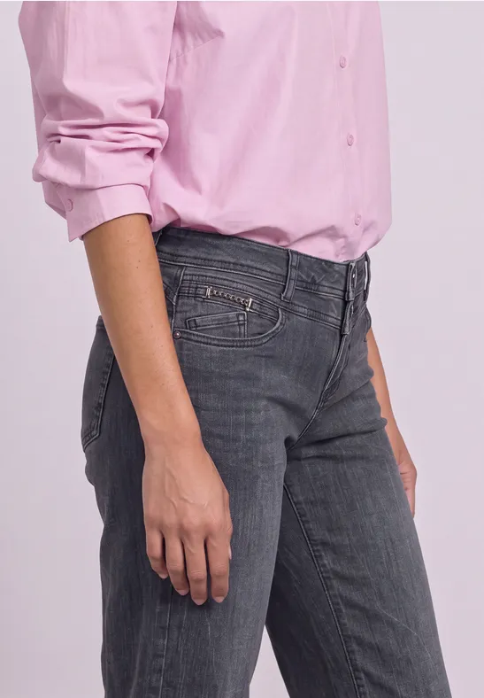 Person in grauen Jeans und rosa Hemd, nur Hüfte, Arm und Hand sichtbar.