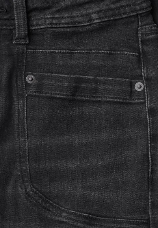 Nahaufnahme einer schwarzen Jeans-Tasche mit Ziernähten und Metallnieten
