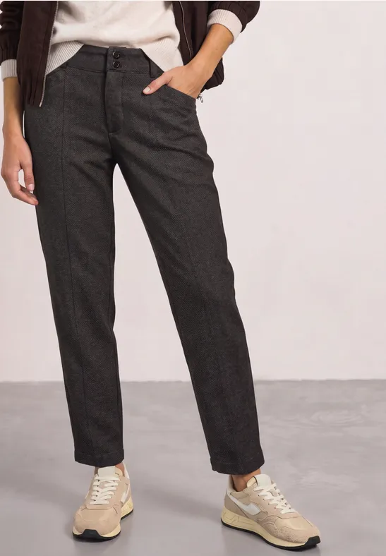 Pantalon gris foncé, coupe droite en Tweed, assorti à des baskets beiges.