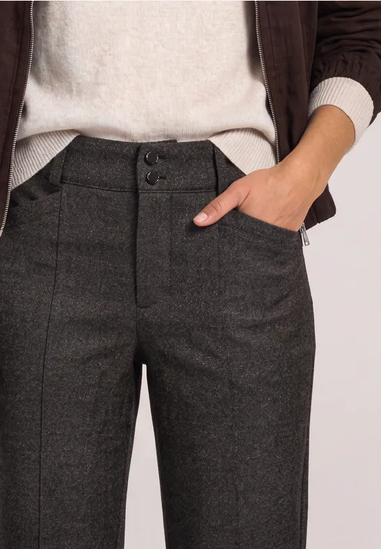 Pantalon femme taille haute gris anthracite à motif subtil, main posée décontractée dans la poche.