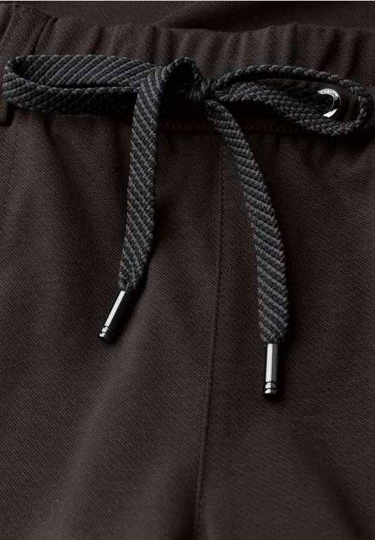 Gros plan du cordon noir sur la ceinture en tissu texturé foncé.